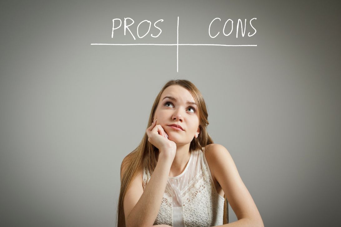 A woman ponders whether and the words pros and cons as evaluates the pros and cons of buying a home before a recession